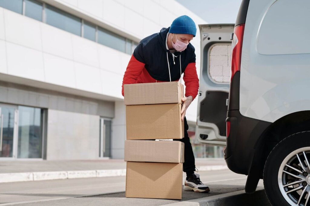 A man wearing a face mask carrying boxes