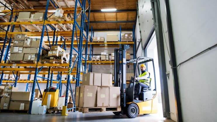 A forklift carrying boxes in a warehouse, illustrating cargo handling, freight logistics, and container load planning.