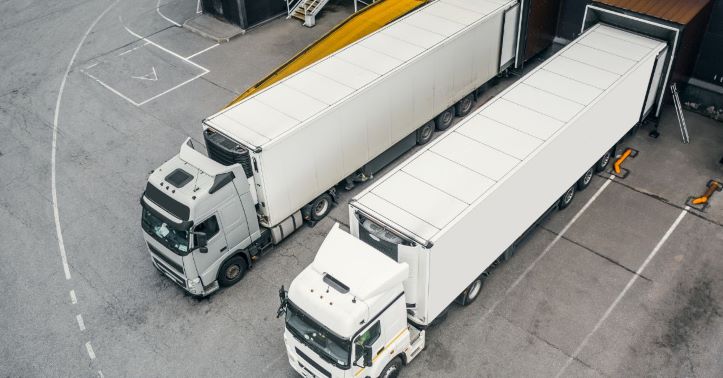 Two trailers parked at a warehouse dock, ready for loading or unloading