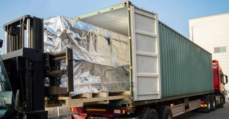 Um empilhador carrega carga para um contentor montado num reboque, o que ilustra um transporte intermodal eficaz e um planeamento otimizado da carga do contentor.