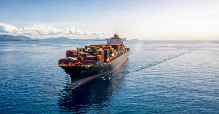 Um grande navio porta-contentores com uma carga completa de contentores, a navegar em mar aberto. Esta imagem realça a importância do transporte marítimo de contentores completos (FCL), em que um único expedidor utiliza exclusivamente um contentor inteiro para a sua carga, o que oferece vantagens como a redução do risco de danos e tempos de trânsito mais rápidos