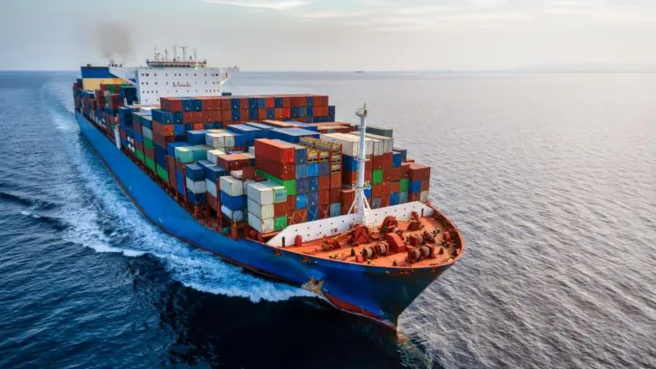 A fully loaded container cargo ship sailing across the open sea, part of international container shipping.