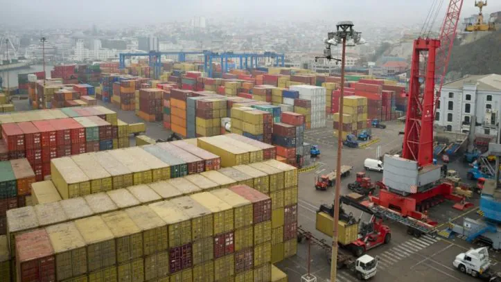 A foggy port with storage freight containers and cargo handling machinery, preparing for international shipping.