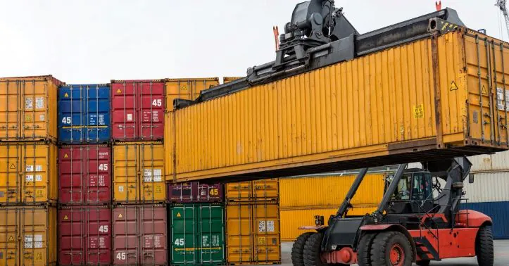 A reach stacker positions a yellow container, illustrating non-stackable goods and loading meter (LDM) space use in a freight terminal.