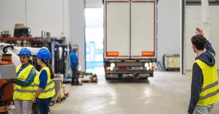 Warehouse workers directing a trailer backing up to the loading dock