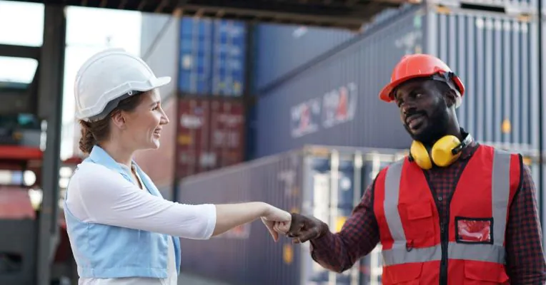 Teamwork and collaboration in logistics operations Two logistics workers bumping fists, symbolizing teamwork and collaboration