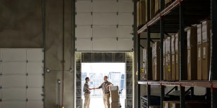 Two warehouse workers are coordinating cargo shipment and preparing goods for container loading