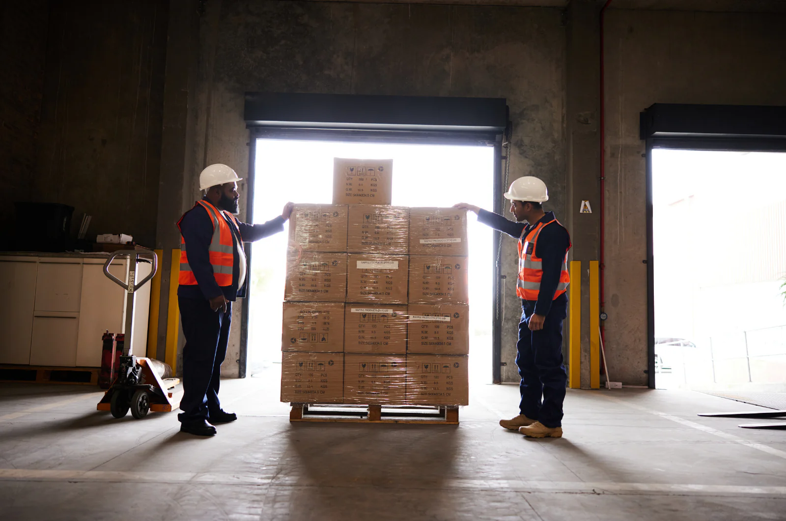 Warehouse workers preparing palletized cargo for loading into a truck in automotive logistics