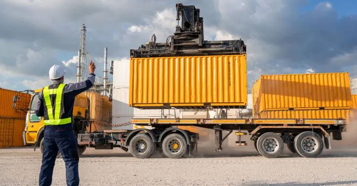 Kontener podnoszony na&nbsp;podwozie naczepy w terminalu intermodalnym