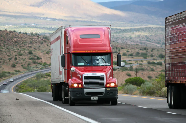 Red semi-truck driving on a highway where accurate load weight calculation is essential for safety and compliance