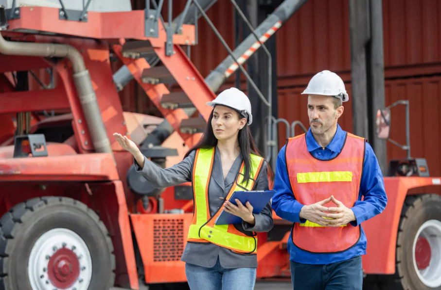 wo workers in safety vests in front of cargo containers discussing pallet loading in logistics.