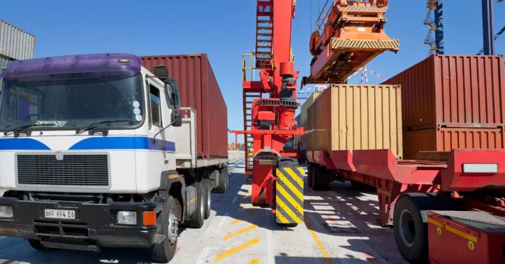 Kontener ładowany na&nbsp;naczepę w terminalu intermodalnym przy użyciu reach stackera